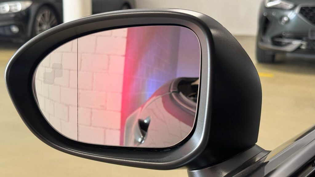 Blick in den Rückspiegel zeigt, dass das Fahrzeug-Heck sich bereits hinter der Ecke einer Mauer befindet (Bremslichter sichtbar). Die Sensoren erkennen dies nicht.